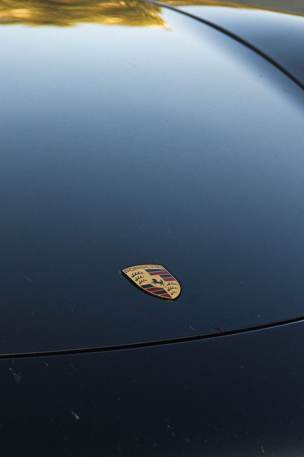Kapota tmavomodrého Porsche so znakom