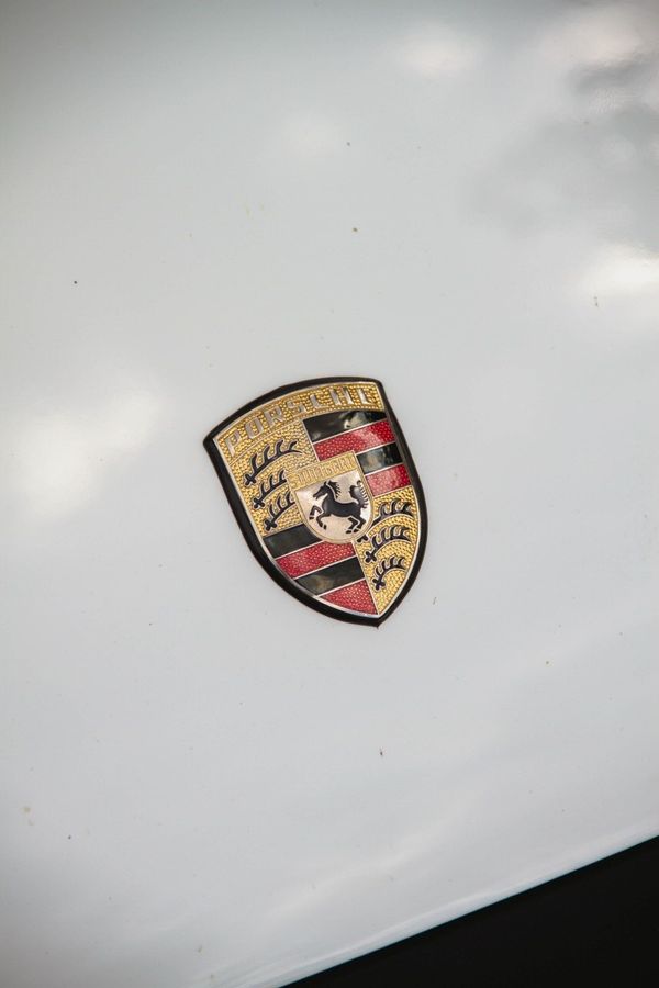 Znak Porsche na bielej kapote